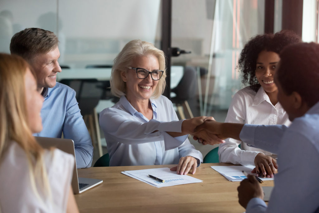 A happy founder shaking hands with her team