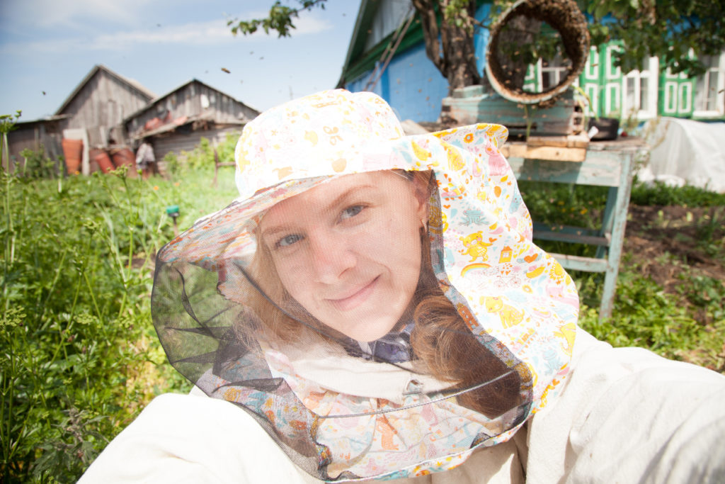 Woman beekeeper making selfie near beehives